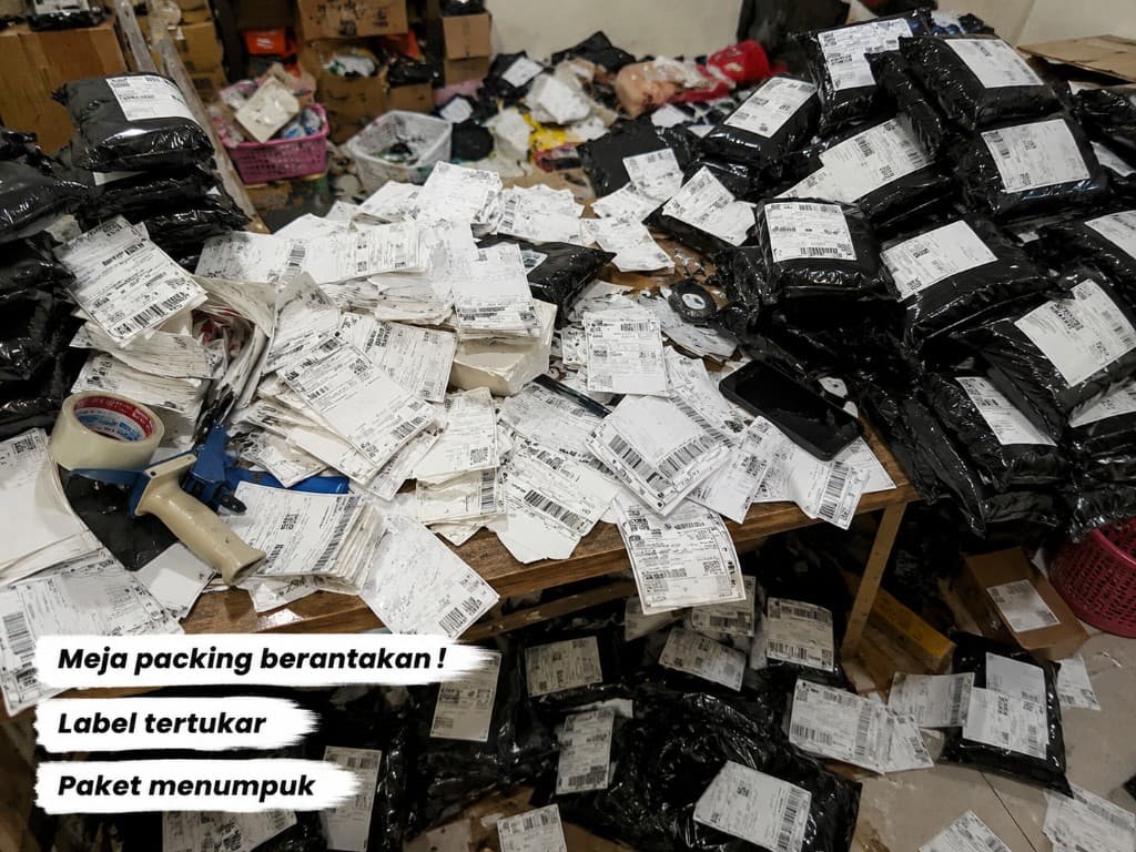 Meja packing berantakan dengan label resi berserakan, paket menumpuk, dan risiko salah kirim tinggi di gudang seller marketplace